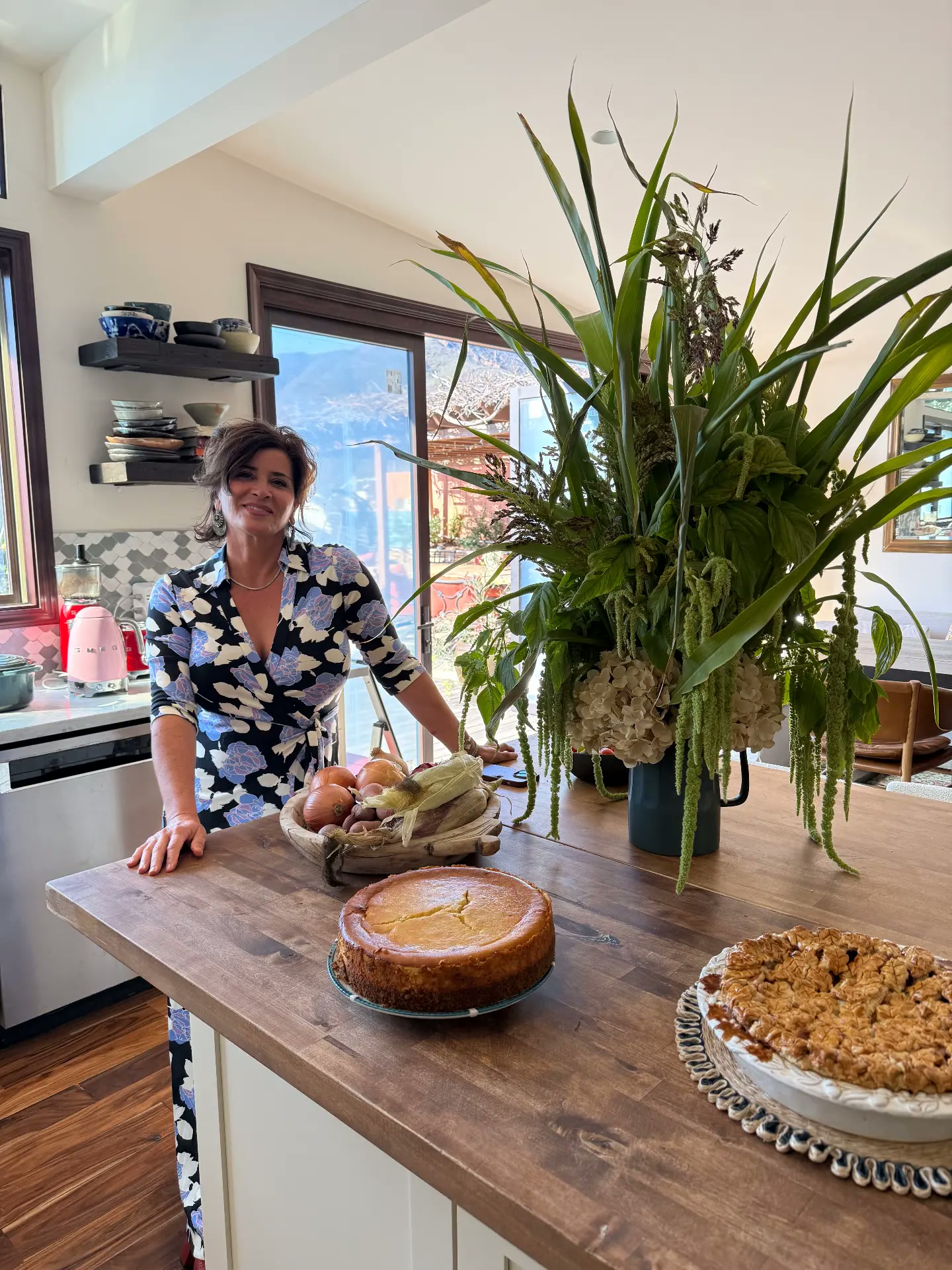 Fiona Afshar at her kitchen table with seasonal produce, flowers, and cakes